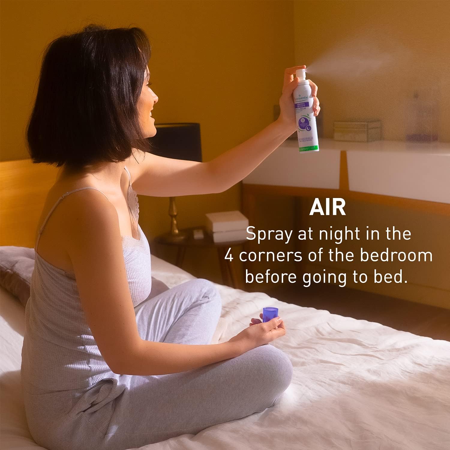 Hand spraying Puressentiel air mist into a bedroom corner.