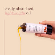 Fushi stretch mark oil being poured from a bottle onto a beige background
