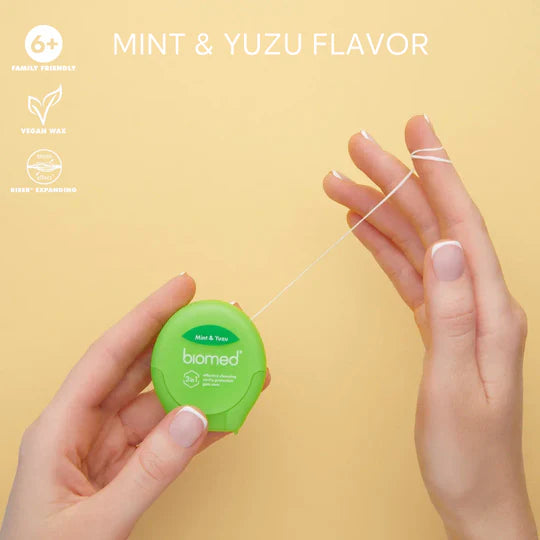Close-up of BIOMED green and white floss stretched between fingers.